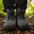 Front view of grey Naturcontact outdoor boots on a forest trail, featuring black laces, metal eyelets, and a rugged sole
