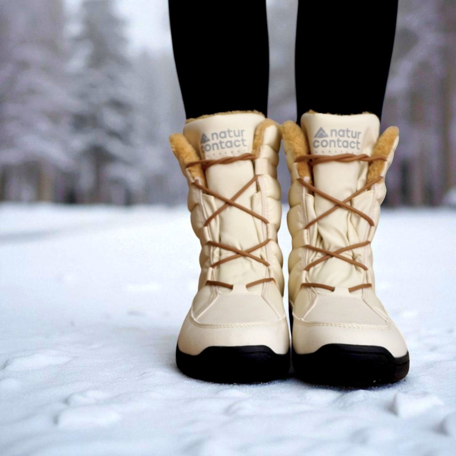 Beige Naturcontact winter boots with brown laces and faux fur lining, worn by a person standing on snow in a winter forest background