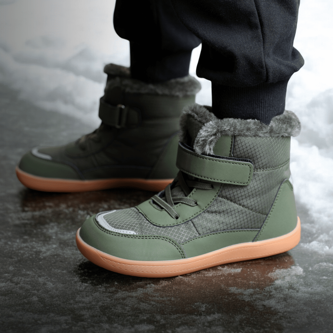 Green winter barefoot boots for kids  with fur lining worn on a snowy ground