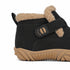 Close-up side view of a black winter boot with beige faux-fur lining, a black hook-and-loop strap with tan details, and a tan sole, shown on a white background.