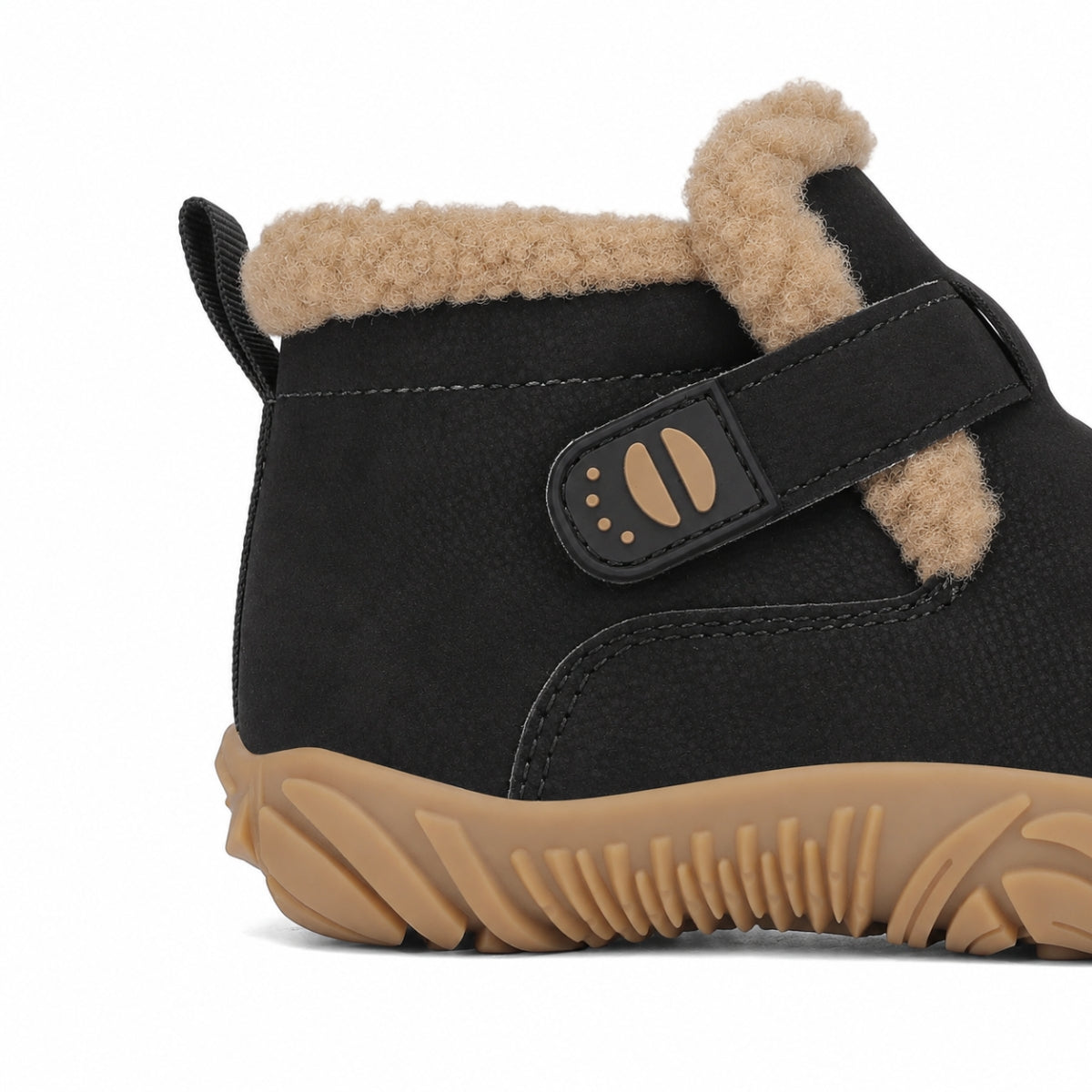 Close-up side view of a black winter boot with beige faux-fur lining, a black hook-and-loop strap with tan details, and a tan sole, shown on a white background.