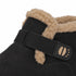 Close-up of a black suede ankle boot with a tan shearling lining and a black strap closure featuring a tan paw-print detail, shown on a white background.